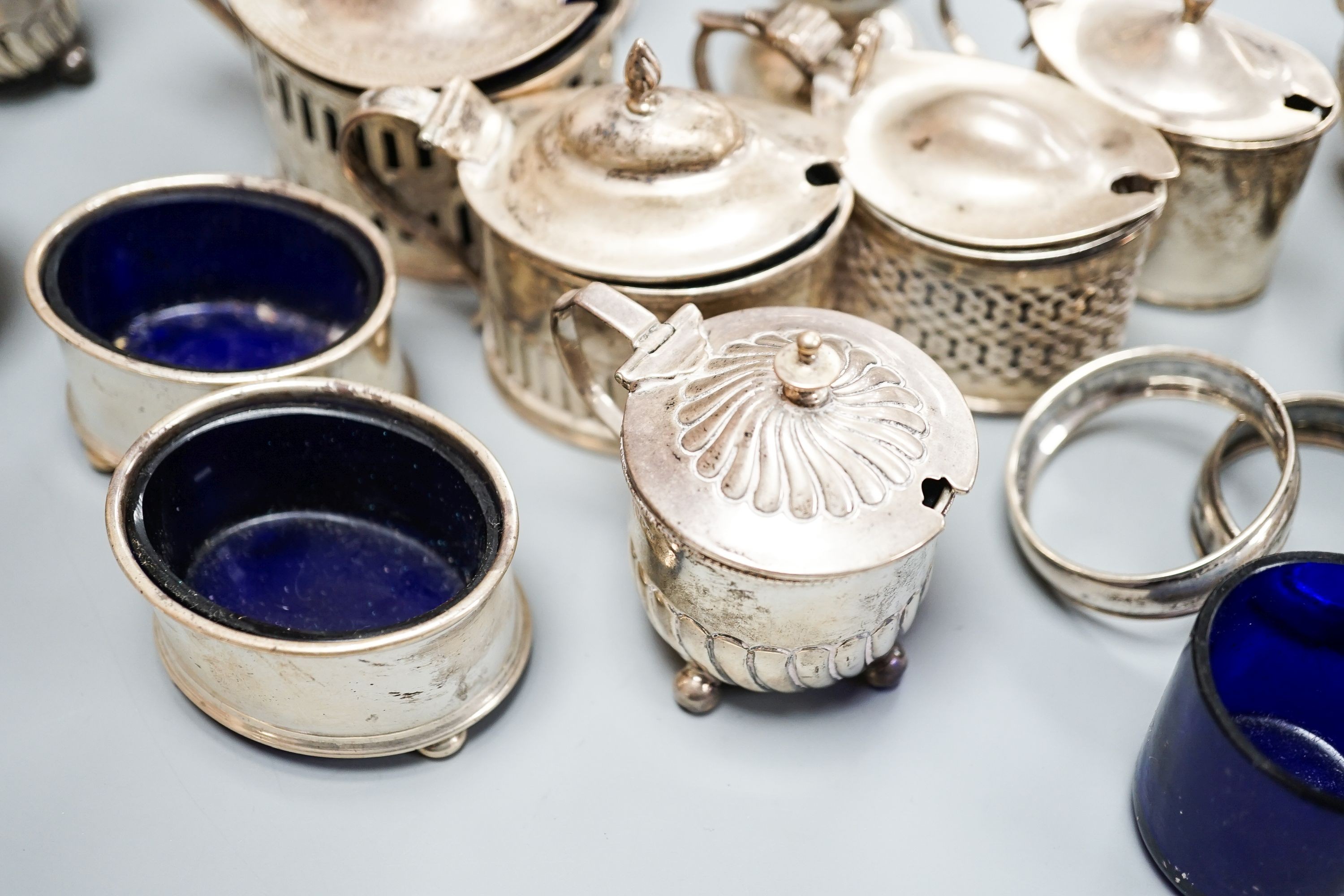 A mixed group of assorted mainly early 20th century silver condiments, including mustard pots, salts and pepperettes, two napkin rings and four plated salts, some lacking liners.